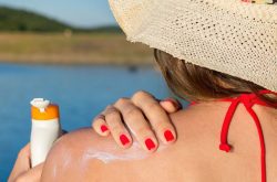 Woman putting sunscreen on shoulder
