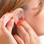 woman putting on hearing aid