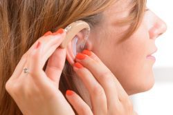 woman putting on hearing aid