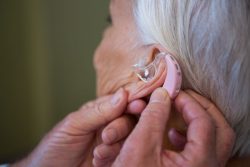 woman putting on hearing aid