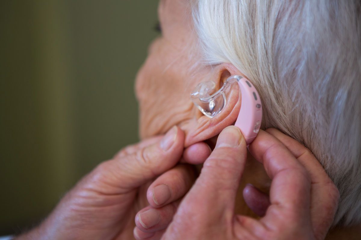 woman putting on hearing aid